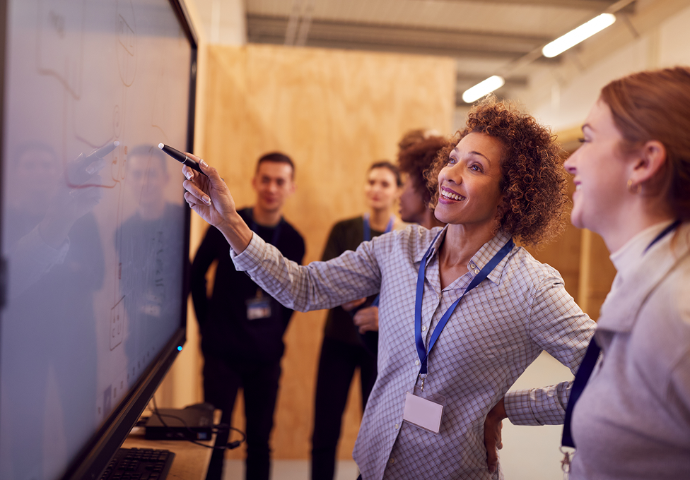 Profissionais utilizando tela interativa Tecmakers em treinamento corporativo